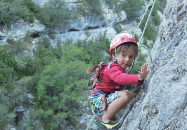 nino escalando con un casco y cuerdas